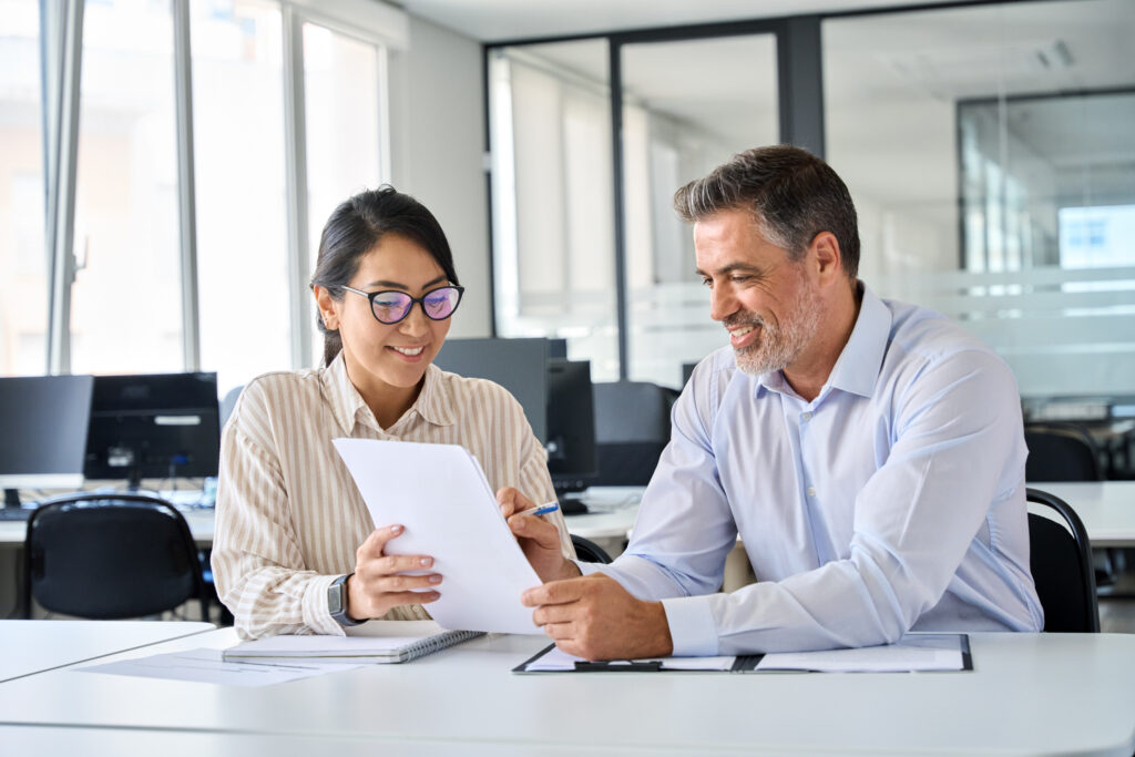 Two colleagues, a male and female, having a friendly discussion over a document