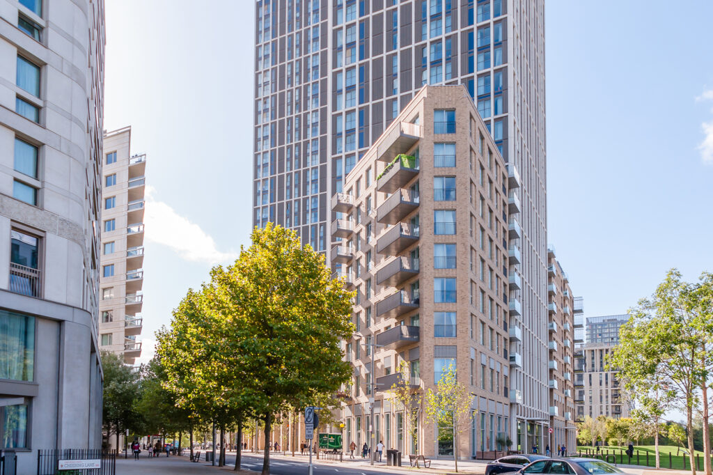 Modern white brick apartment block in town along a tree lined avenue